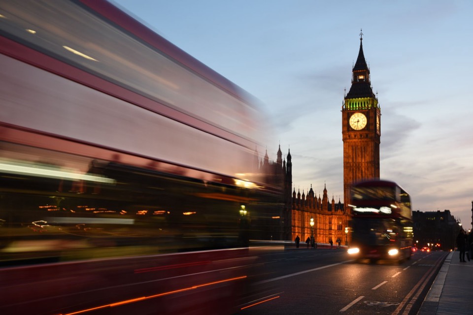 Big Ben and red London buses at dusk, seen from Westminster Bridge